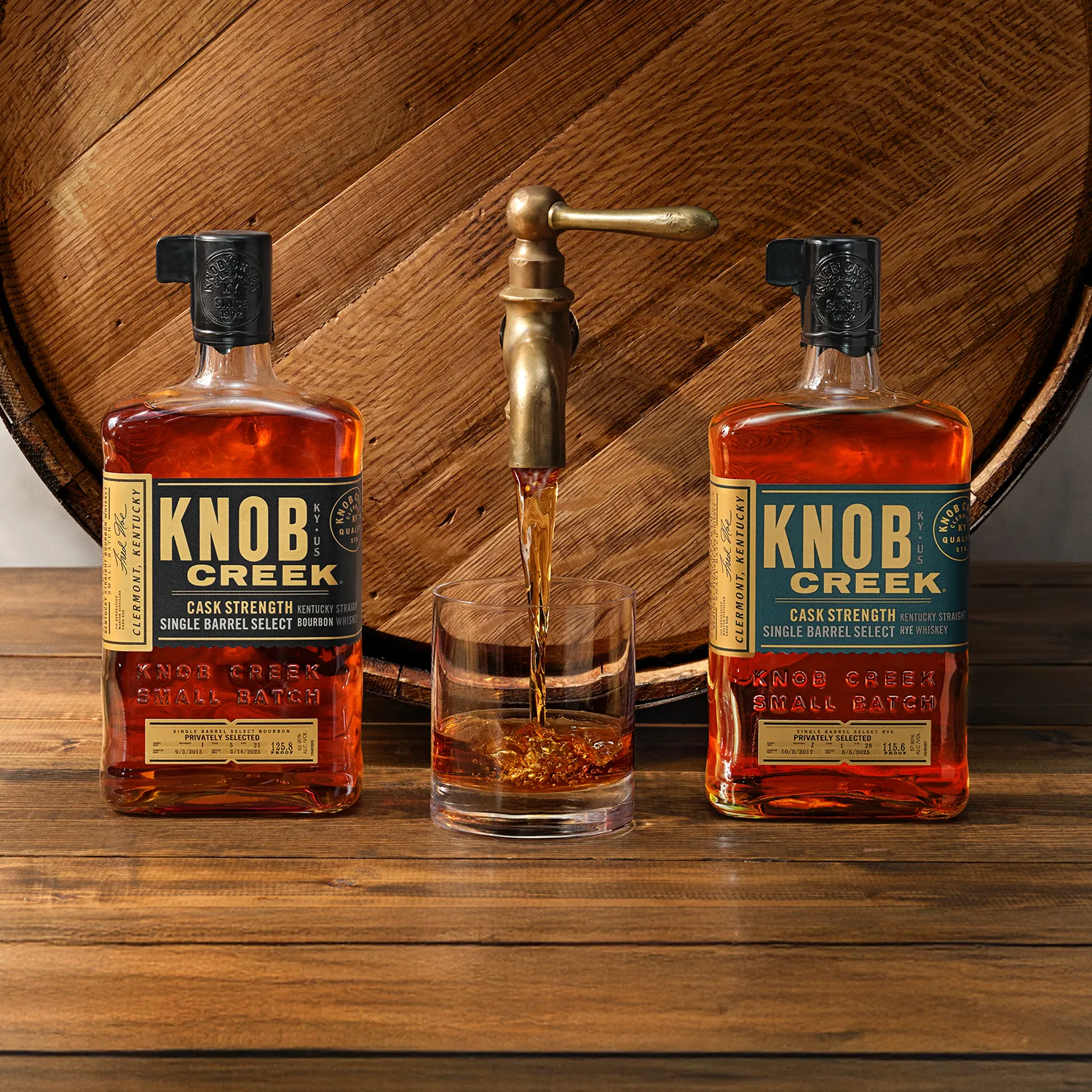 Two bourbon bottles placed beside a wooden barrel, showcasing a rustic distillery setting.